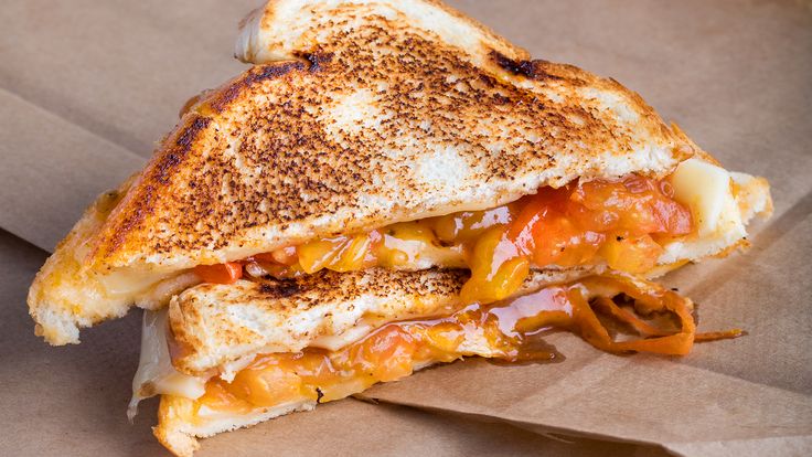 a grilled cheese and tomato sandwich sitting on top of a brown paper wrapper