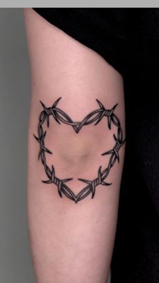 a heart shaped tattoo with barbed wire on the side of her leg, which is black and white