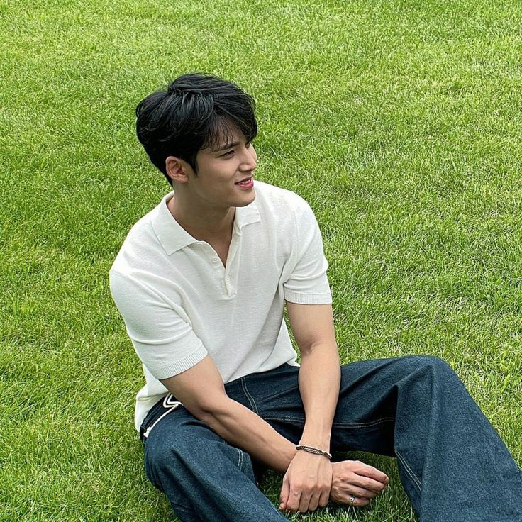 a man sitting in the grass with his hands on his knees