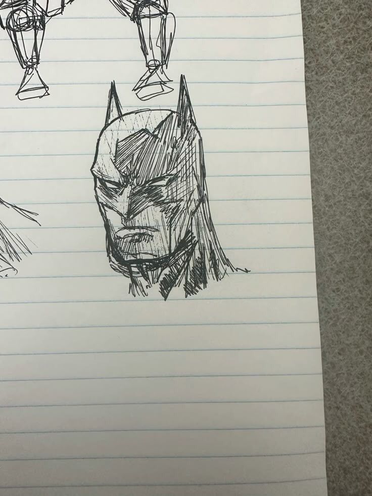 a drawing of two batman masks on lined paper