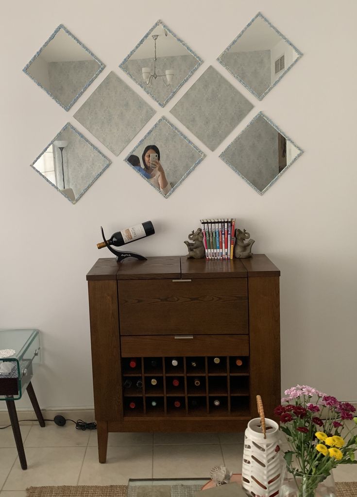 a wooden cabinet sitting in front of a wall with three mirrors on top of it