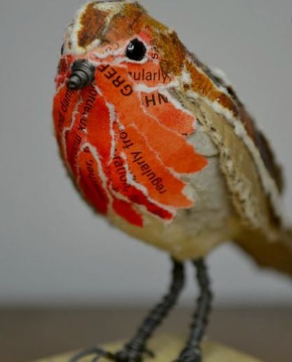 a small bird sitting on top of a wooden block with words written in red and orange