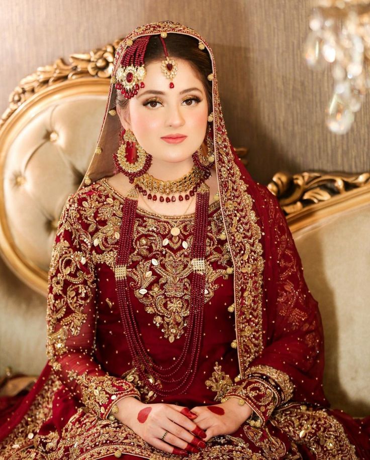 a woman sitting on top of a couch wearing a red dress and headpieces