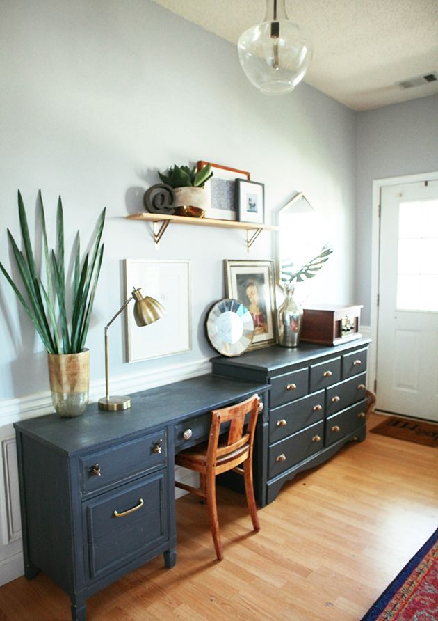 a room with a desk, chair and potted plant on the wall next to it