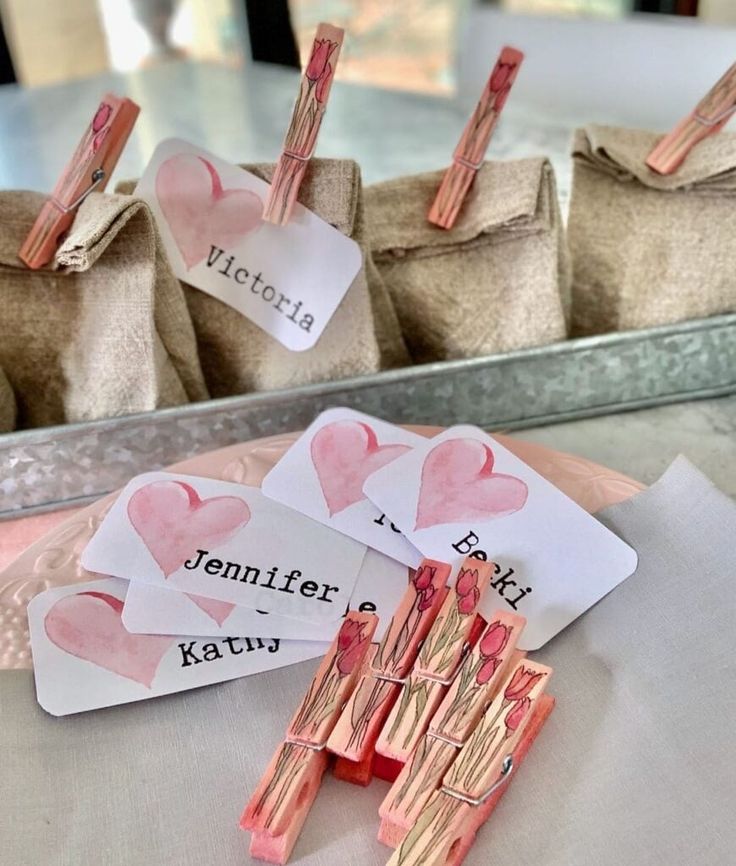 some pink lipstick sticks are sitting on a table next to small bags with tags that say victoria