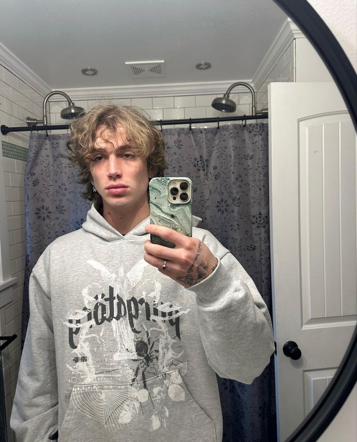 a young man taking a selfie in front of a mirror with his cell phone