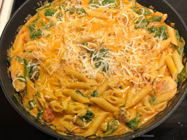 a skillet filled with pasta and cheese on top of a stove