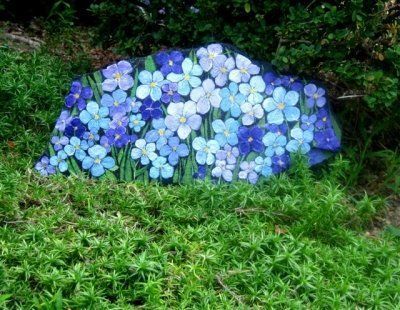 a rock with flowers painted on it in the grass