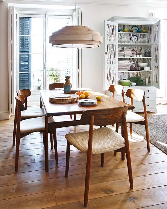 a dining room table and chairs in front of a bookcase with open shelves on the wall