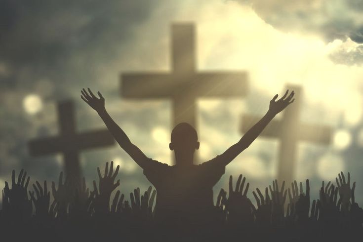 a person standing in front of a cross with their hands raised up to the sky