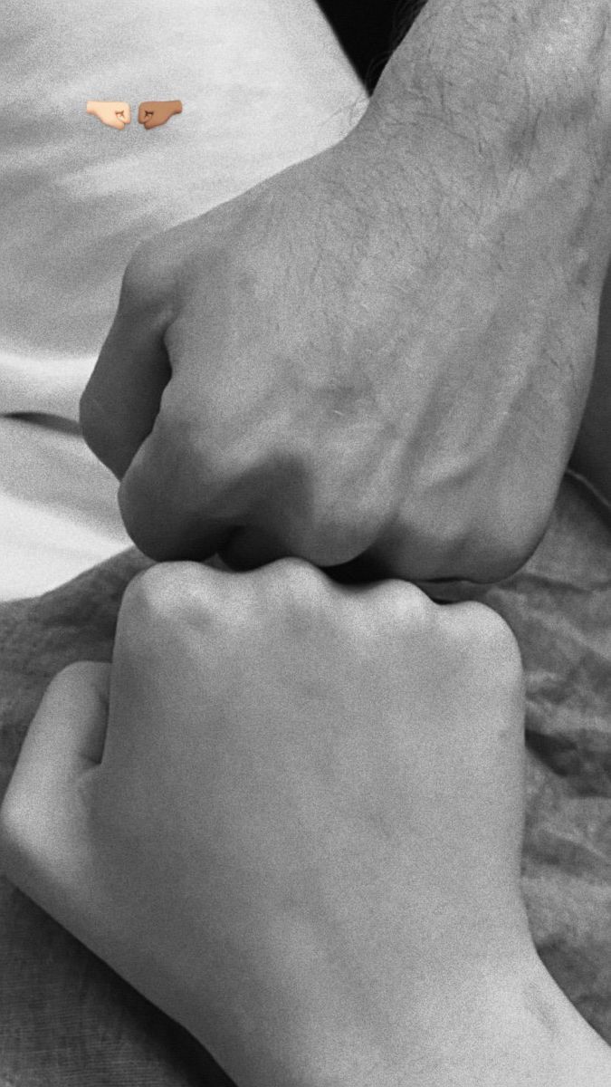 two hands touching each other while laying in bed