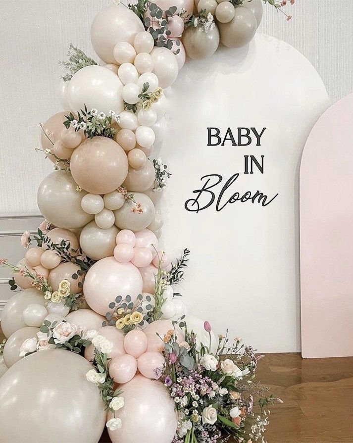 a baby in bloom balloon arch with flowers and balloons attached to the front of it