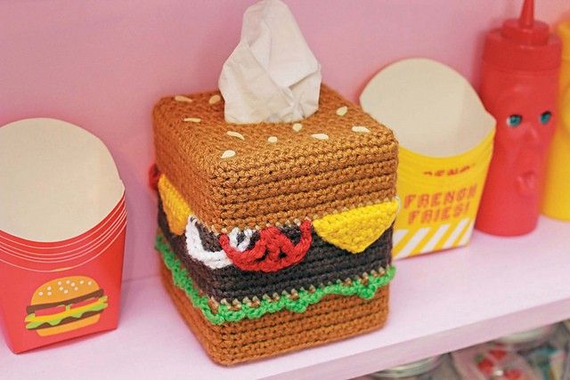 a crocheted hamburger sitting on top of a shelf next to other food items