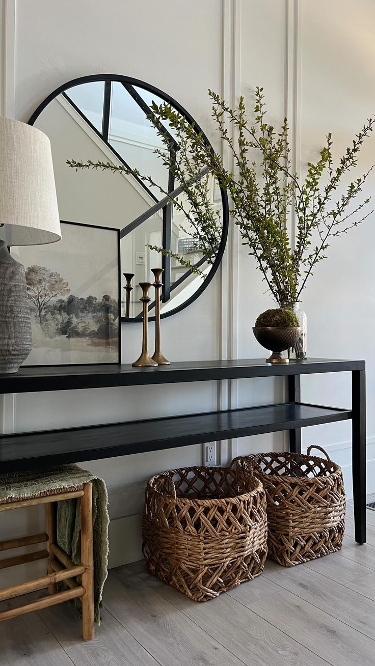 a black shelf with two baskets and a large round mirror on the wall above it