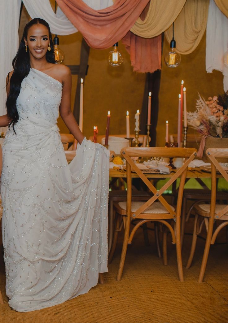 a woman in a white dress standing next to a table