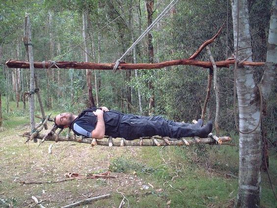 a man laying on a log in the woods