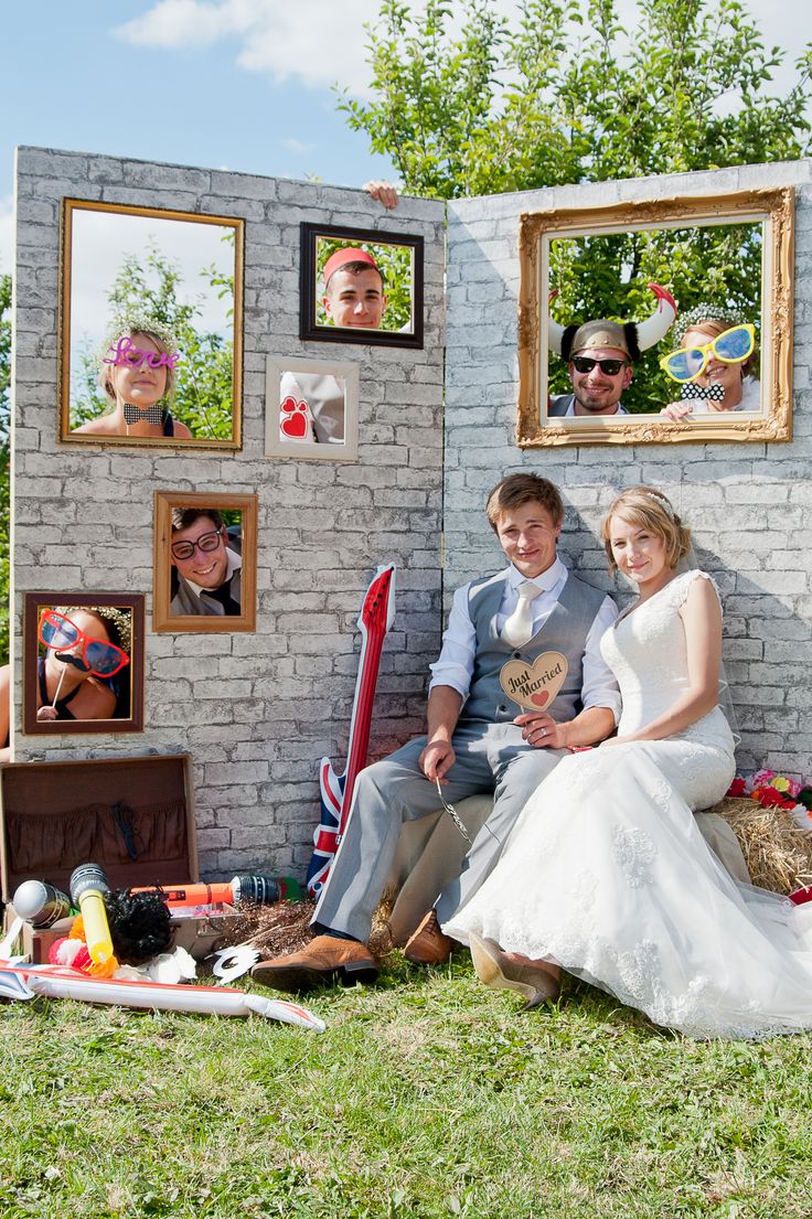 a man and woman sitting next to each other in front of a brick wall with pictures on it