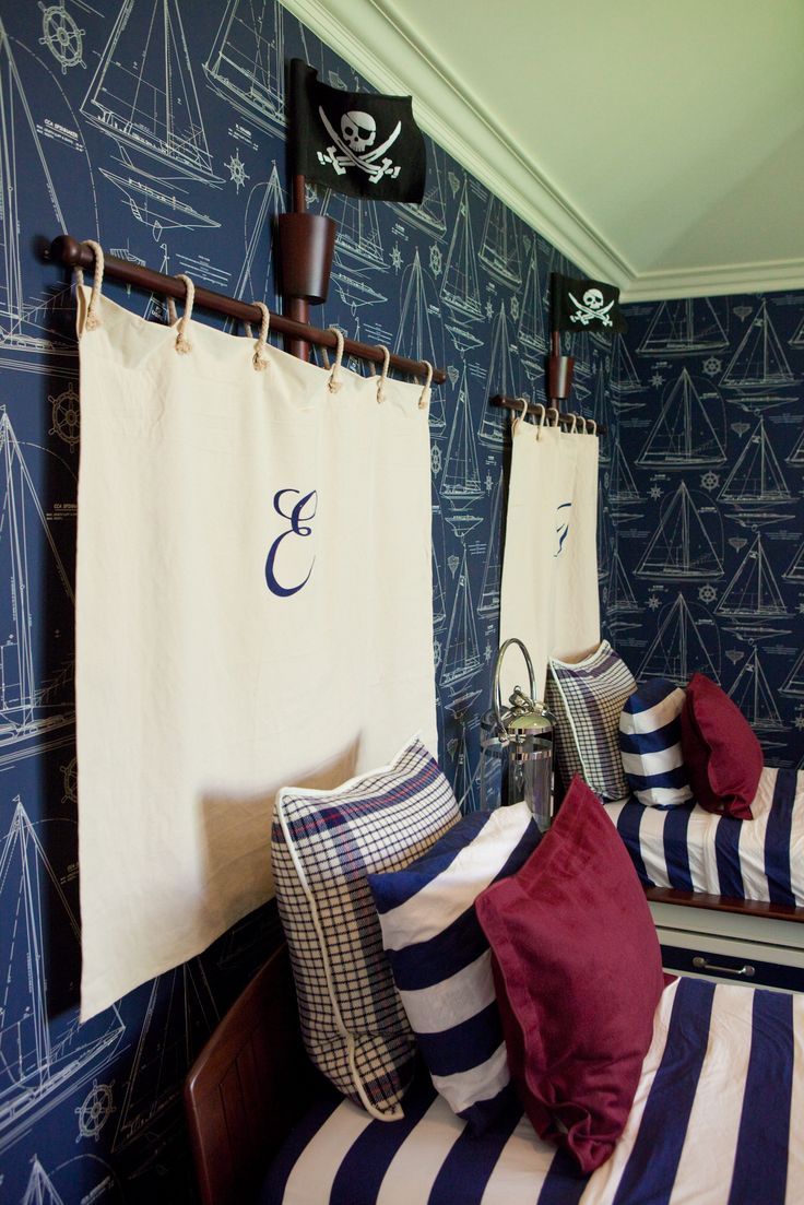 two twin beds in a room with blue and white wallpaper, one is made up as a pirate ship