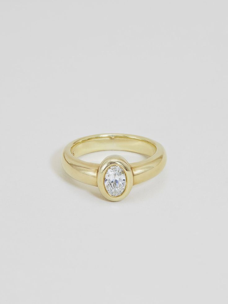 a yellow gold ring with a single diamond in the center, on a white background