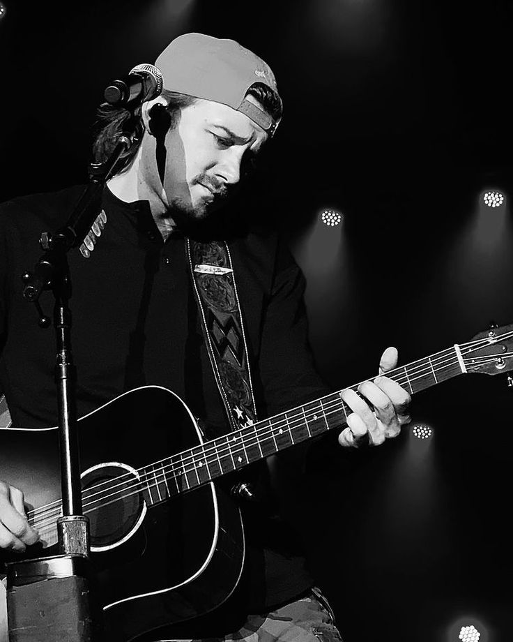 a man playing an acoustic guitar on stage