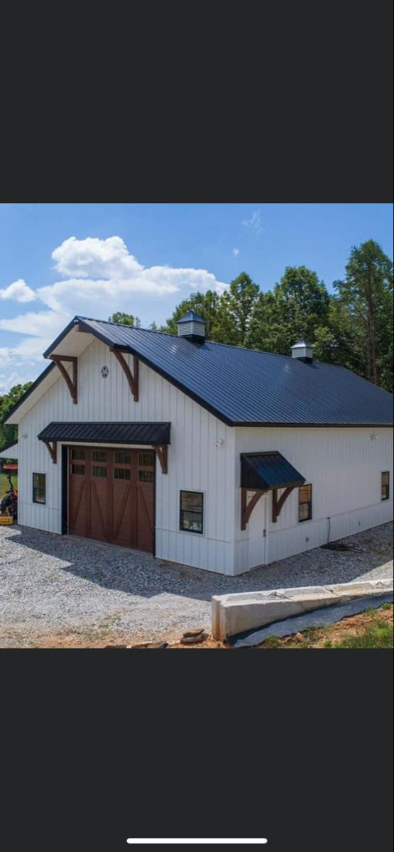 a large white barn with two garages on the front and one attached to it