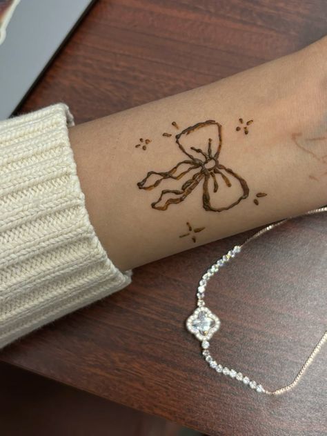 a woman's arm with a tattoo on it that has a bow and beads