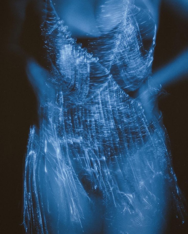 a blurry image of a woman's body in blue light with her hands on her hips