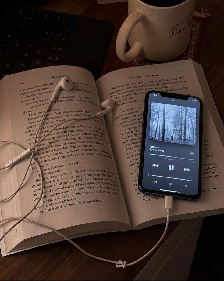 an open book sitting on top of a wooden table next to a cup of coffee