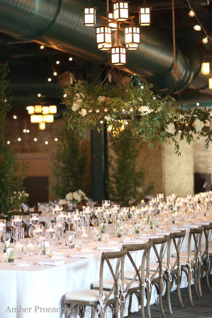 the tables are set up with white linens and greenery for an elegant wedding reception