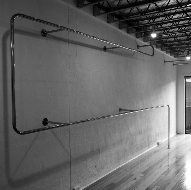 an empty room with wood flooring and metal railings on the wall, in black and white