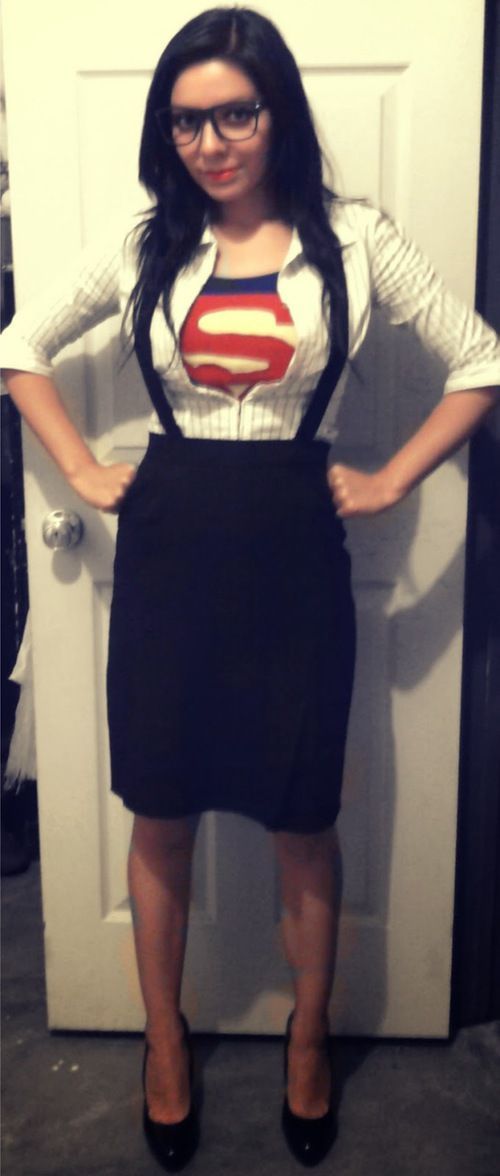 a woman standing in front of a white door wearing a superman shirt and black skirt