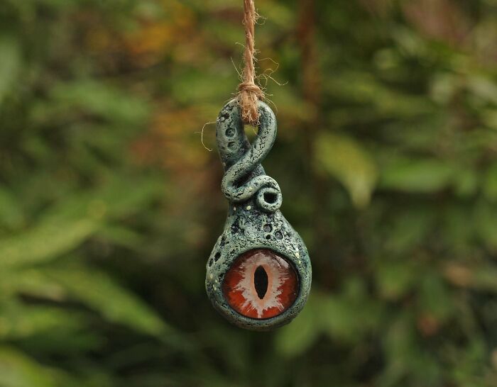 an ornament hanging from a rope with a red eyeball in the center