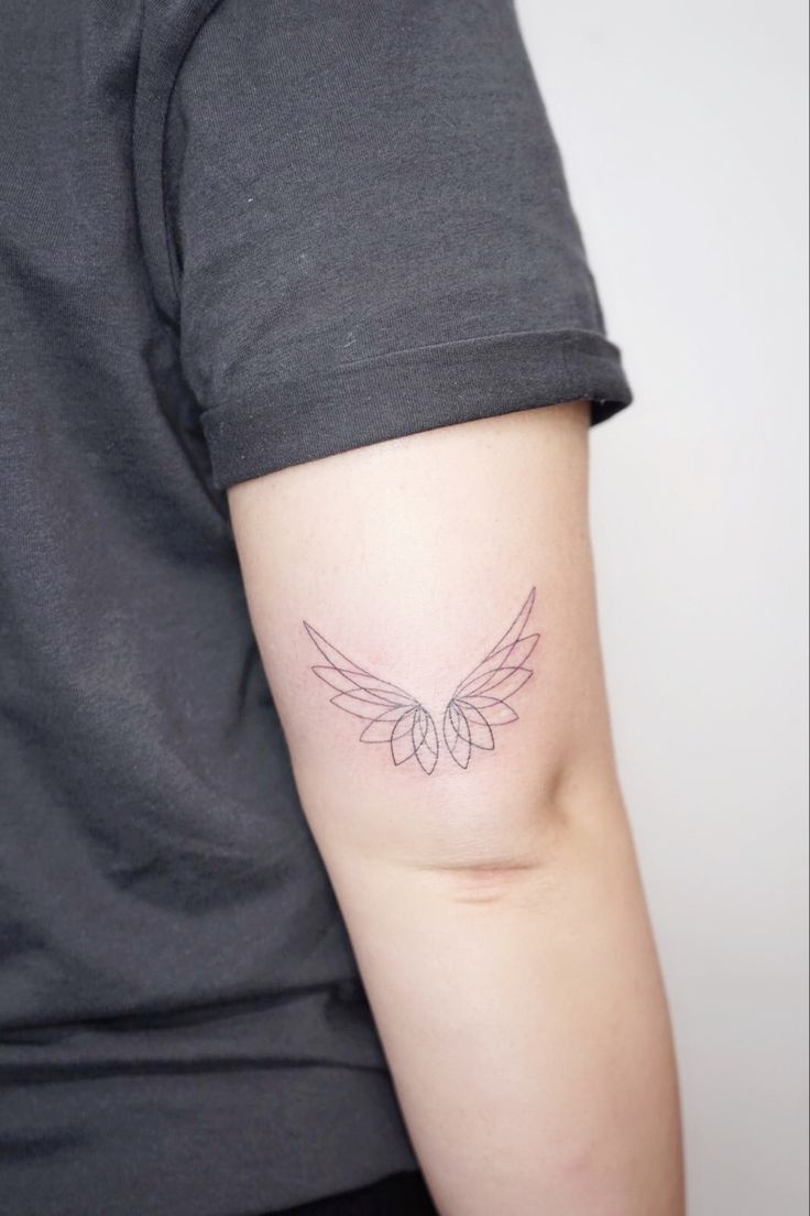 a woman's arm with a tattoo on the back of her left arm and wings