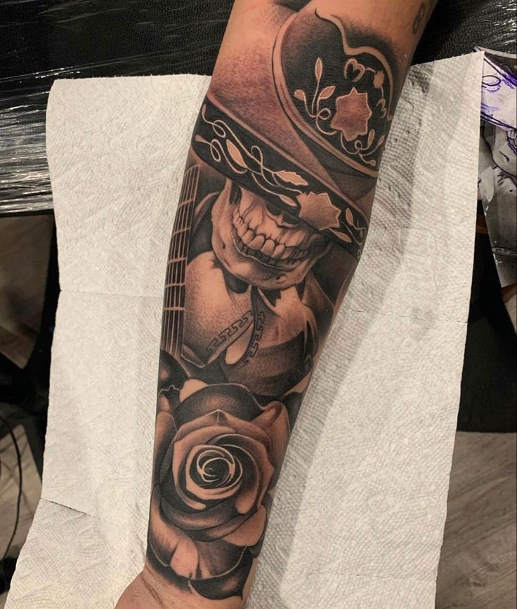 a man with a skull and roses tattoo on his arm