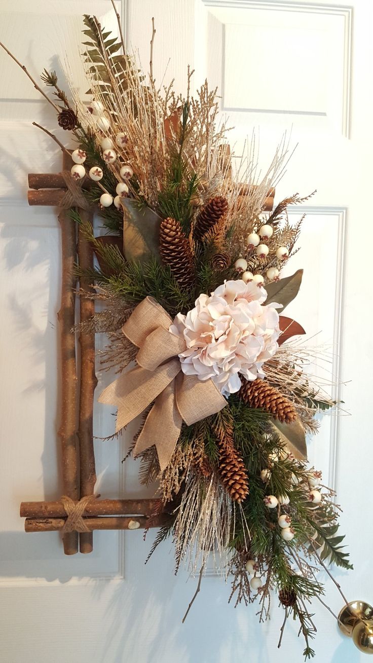 a wreath is hanging on the door with pine cones, berries and other greenery