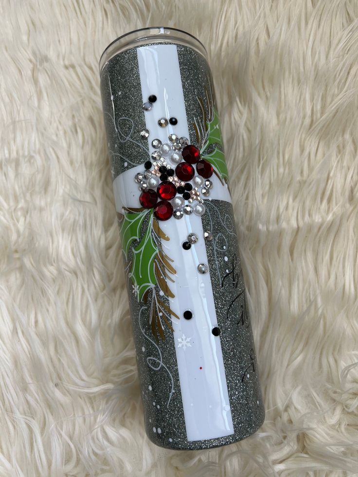 a christmas themed tumbler with red and white decorations on it sitting on a furry surface