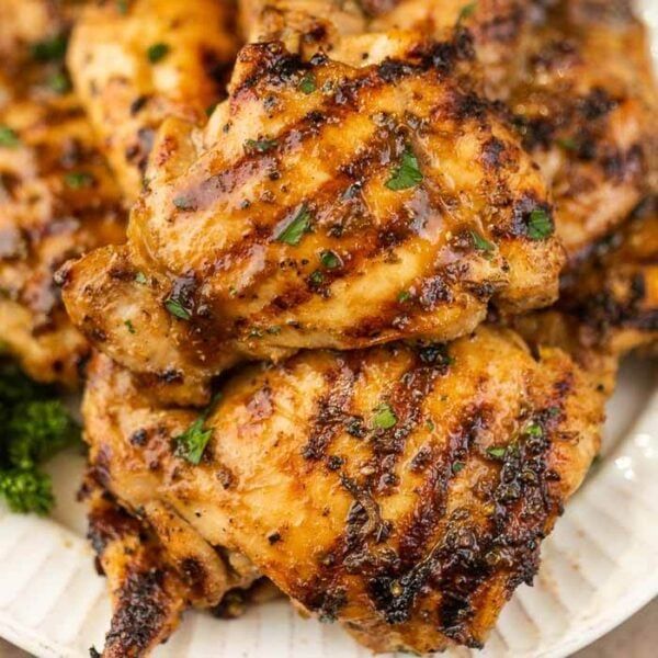 grilled chicken on a plate with broccoli and parsley in the background