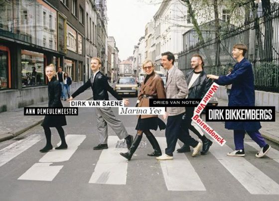 a group of people walking across a street holding onto a sign that says drink and save