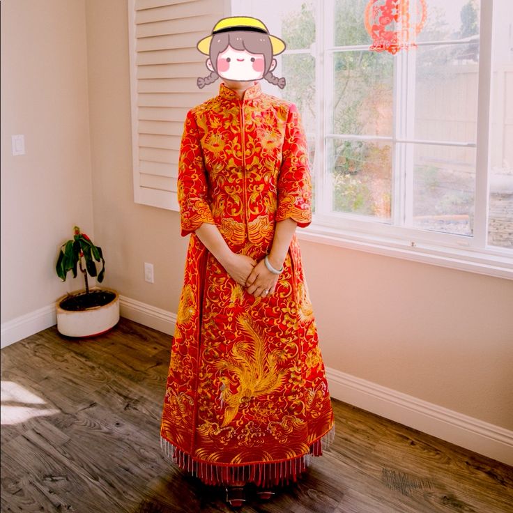 a woman standing in front of a window wearing an orange dress and hat with a monkey on it's head