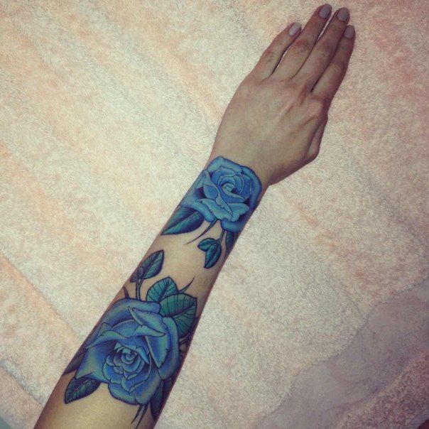 a woman's arm with blue roses on it and her hand in the air