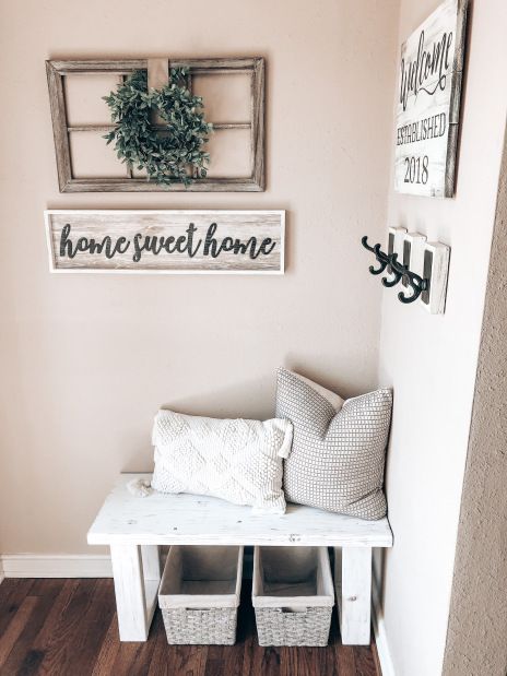 a bench with two baskets underneath it and some signs on the wall behind it that say home sweet home