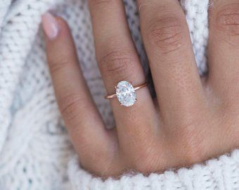 a close up of a person's hand with a diamond ring on their finger