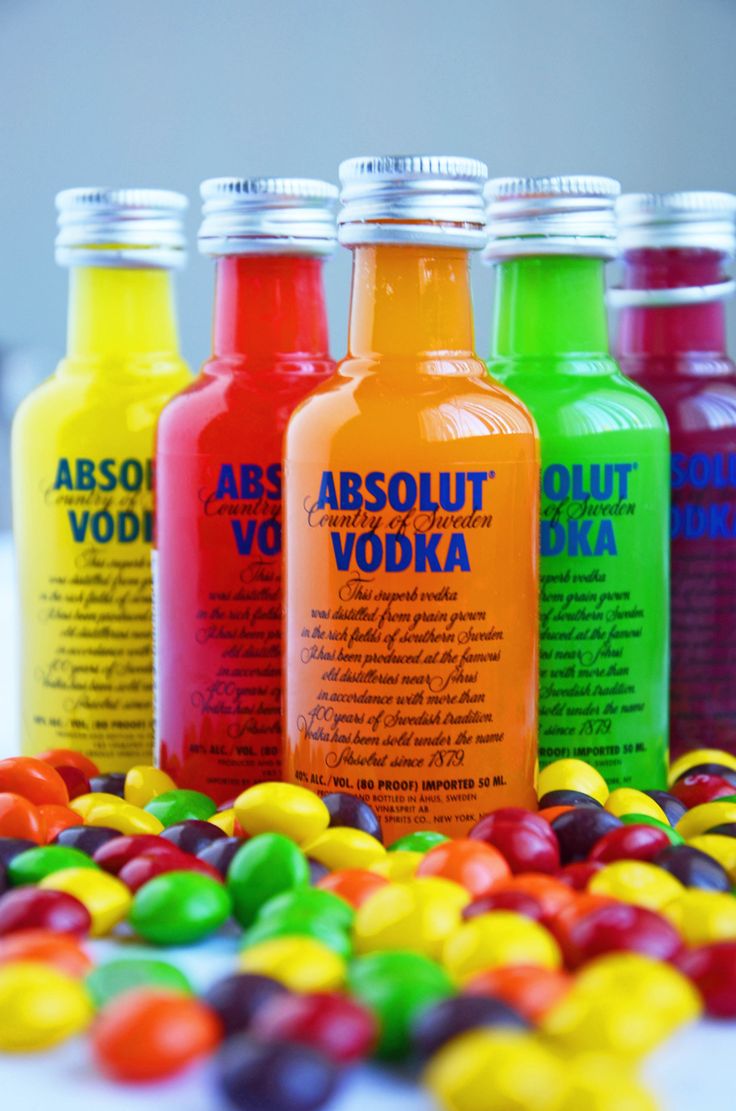 four bottles of vodka sitting next to each other on top of candy candies in front of them