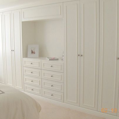 a bedroom with white furniture and carpeted flooring