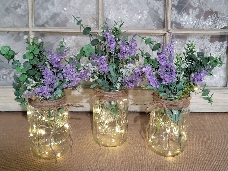 three mason jars filled with purple flowers and greenery