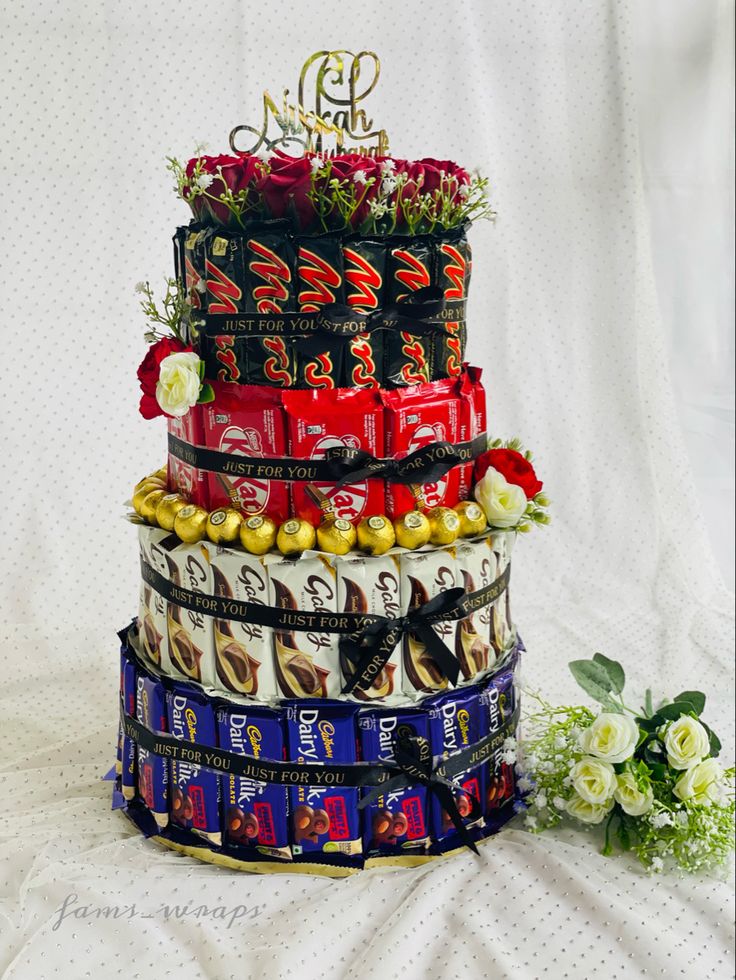 a multi tiered cake made out of chocolates and flowers on a white tablecloth