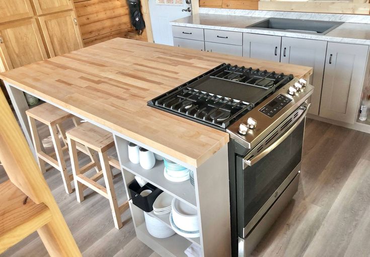 a stove top oven sitting inside of a kitchen next to a wooden counter and stools