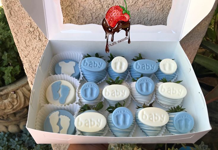 a box filled with blue and white chocolates covered in frosting next to a strawberry