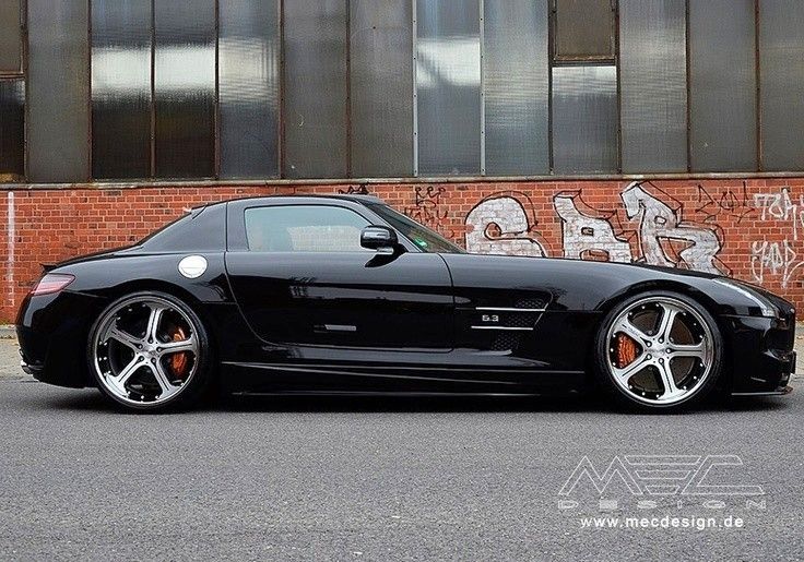 a black sports car parked in front of a brick building with graffiti on the wall