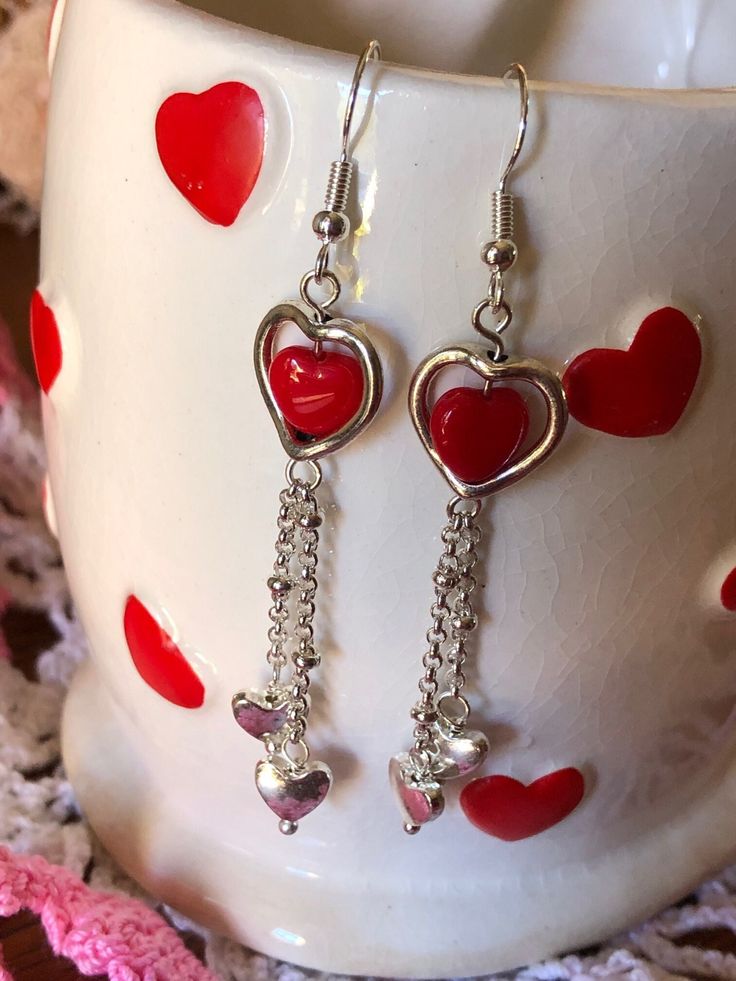 These red glass heart bead dangle earrings make a simple and delicate touch to any outfit whether you wear them for Valentine's Day or just any day. Silver-toned findings and nickel-free ear wires complete the set. Do not wear earrings when bathing or swimming. Avoid getting hairspray, perfume or lotions on them. Wipe with a soft damp cloth if required. Red Heart-shaped Metal Earrings, Red Heart Charm Metal Earrings, Metal Heart Beaded Earrings For Gifts, Metal Heart Beads Earrings For Gifts, Heart Beads Metal Earrings For Gift, Heart-shaped Dangling Charms Jewelry For Valentine's Day, Heart-shaped Jewelry With Dangling Charms For Valentine's Day, Gift Metal Heart Earrings With Heart Beads, Valentine's Day Metal Heart Dangle Earrings